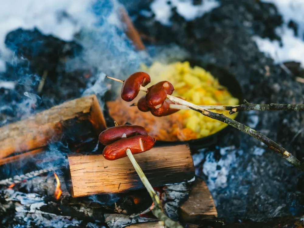 Würstchen über einem Lagerfeuer im Schnee
